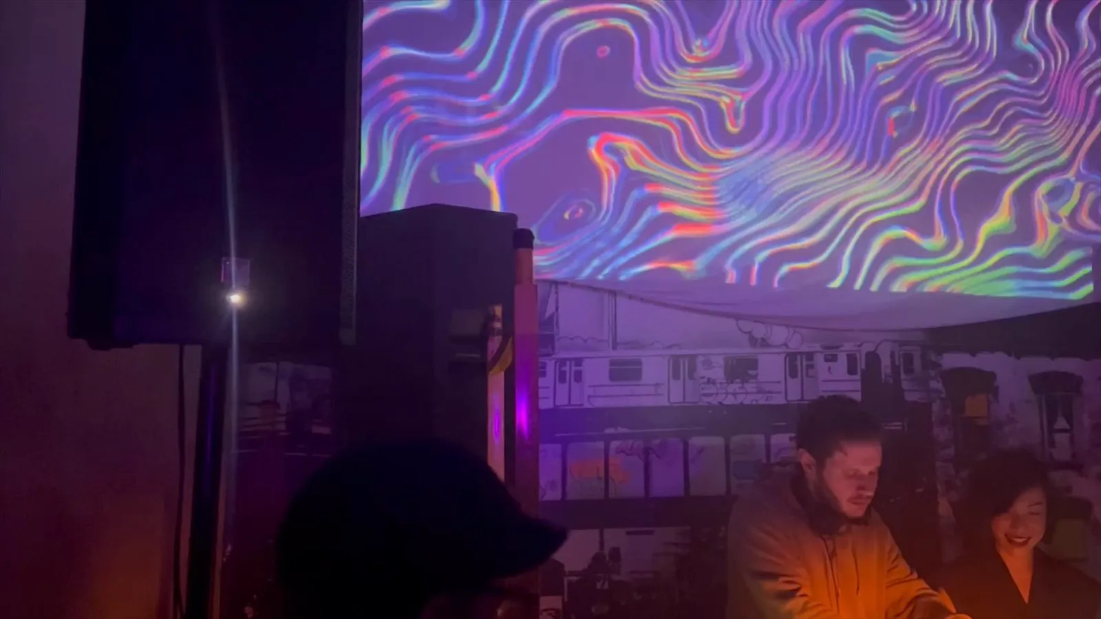 Audio-reactive visuals projected behind a DJ booth
